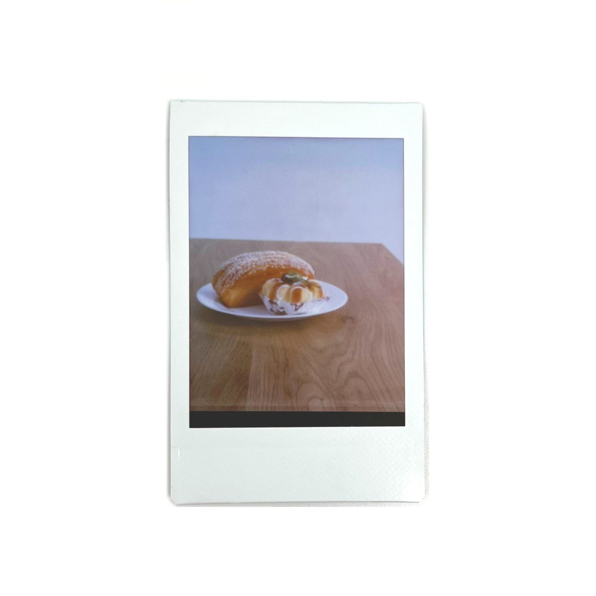 An instant photo captured with a Jollylook Pinhole Mini camera, set against a white background. The photo showcases a plate of delicious cakes