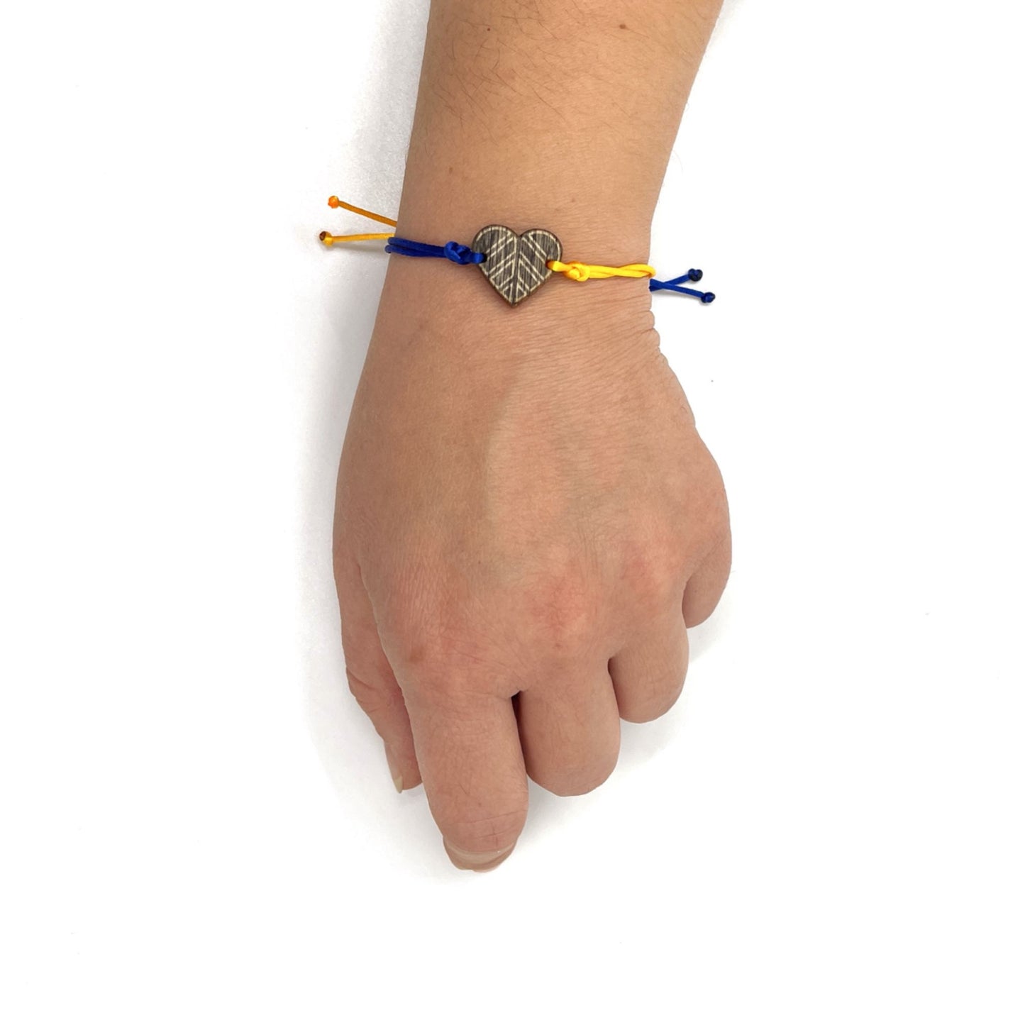 A hand adorned with the colorful bracelet 'Peace for Ukraine.' The hand is against a white background