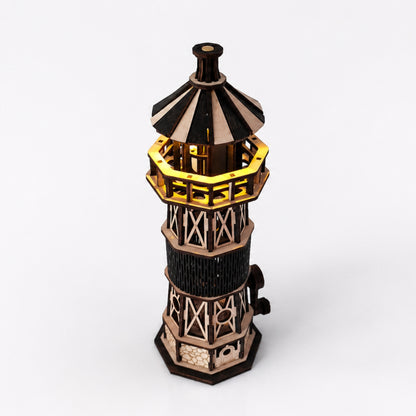 Jollylook Kinetic Lighthouse wooden mechanical model kit assembled and lit on a tabletop. It has a real working light with three modes: warm, cold, and mixed. 