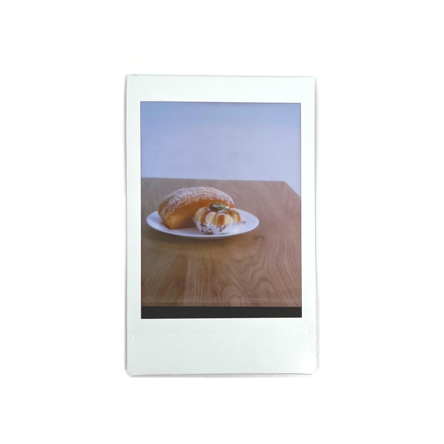  An instant photo captured with a Jollylook Pinhole Mini camera, set against a white background. The photo showcases a plate of delicious cakes